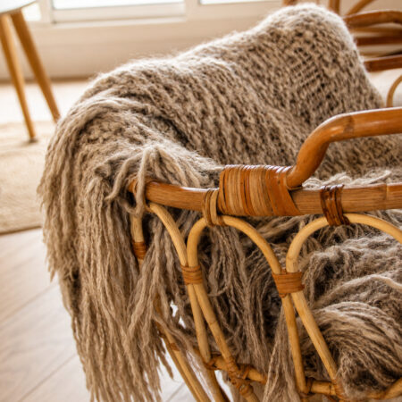 Panier en otin habillé d'un plaid en laine dans un appartement rénové après sinistre à Nantes.