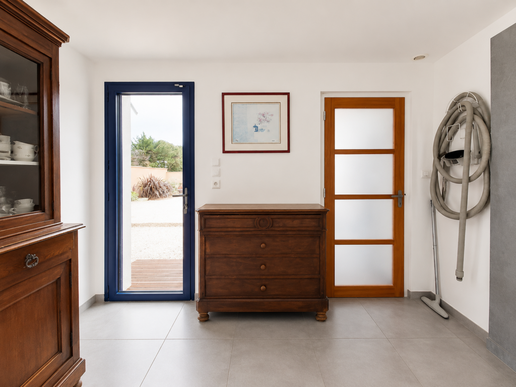 Avant travaux de l'arrière-cuisine buanderie multifonction à Damgan montrant l'accès extérieur, une commode ancienne et les volumes existants avant le futur agencement sur mesure.