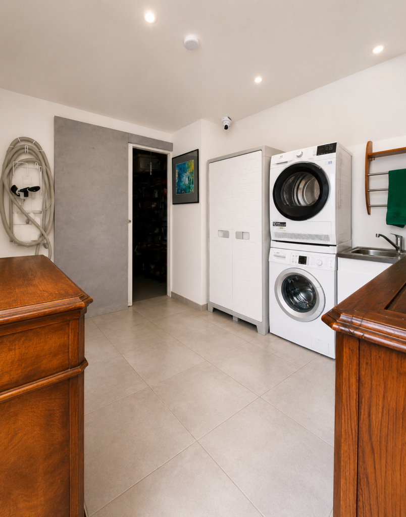 Avant rénovation de l'arrière-cuisine buanderie multifonction à Damgan présentant l'espace buanderie avec colonne lave-linge, sèche-linge, rangements et évier.