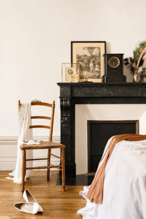 Chambre rénovée avec cheminée en marbre noir, parquet ancien et décoration dans une rénovation d'appartement ancien à Nantes.