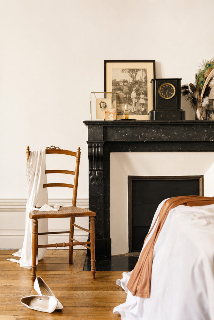 Chambre rénovée avec cheminée en marbre noir, parquet ancien et décoration dans une rénovation d'appartement ancien à Nantes.