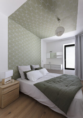 Chambre aux tons vert sauge avec papier peint graphique au plafond et mobilier blanc dans une décoration complète de maison à Nantes.