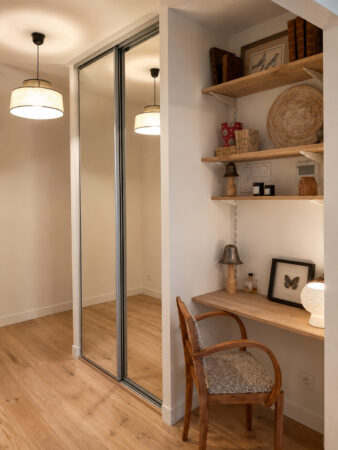 Espace bureau intégré avec étagères en bois et placard sur mesure dans un appartement rénové après sinistre à Nantes.