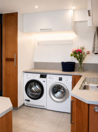 Vue du sèche-linge, du lave-linge et du plan de travail d'une arrière-cuisine buanderie multifonction sur mesure à Damgan.