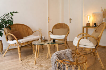 Coin salon rénové après sinistre à Nantes avec fauteuils et canapé en rotin, table basse en verre et décoration naturelle.