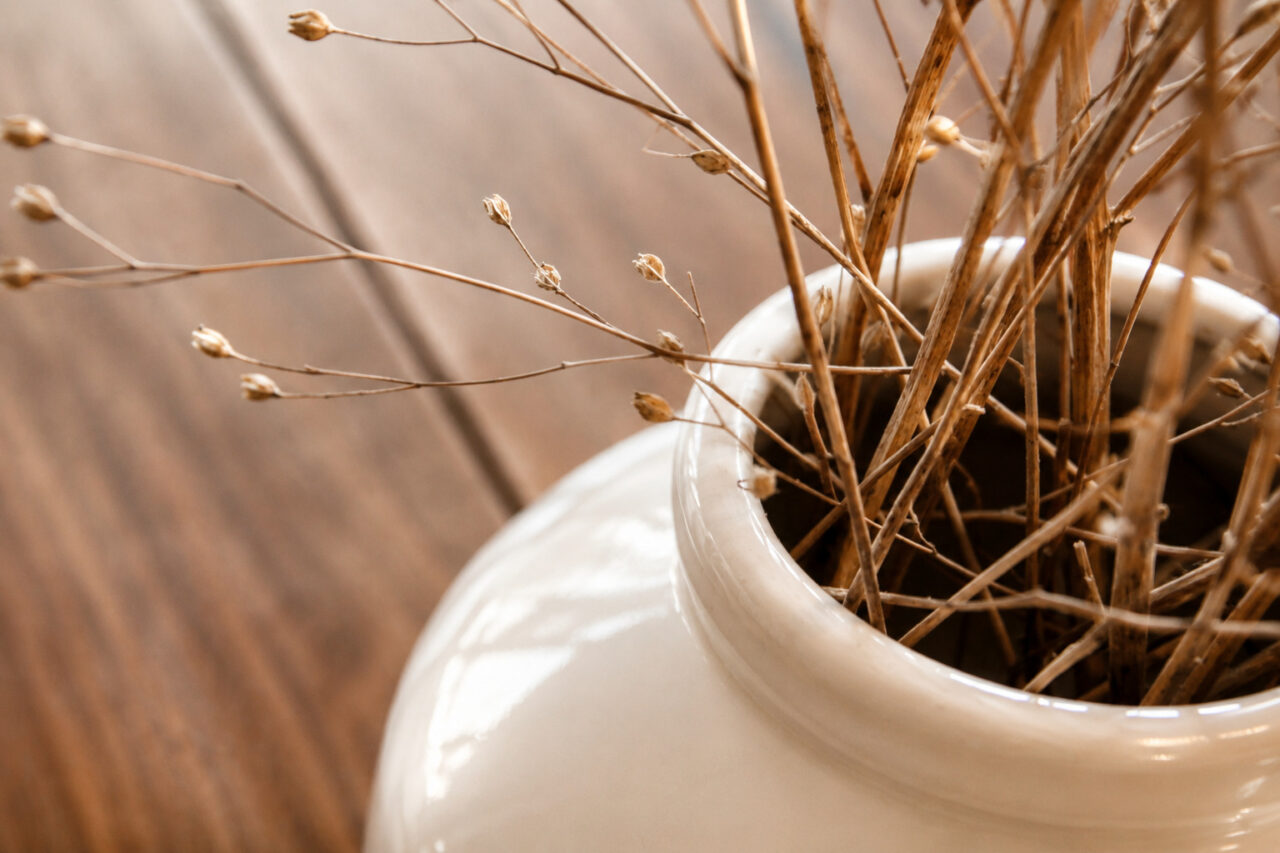 Vase décoratif et fleurs séchées sur une table en bois dans un appartement rénové après sinistre à Nantes.