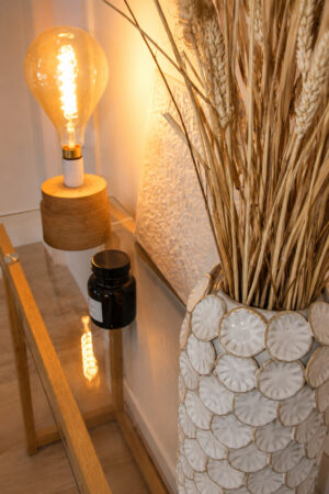Console décorative avec lampe, vase en céramique et fleurs séchées dans un appartement rénové après sinistre à Nantes.