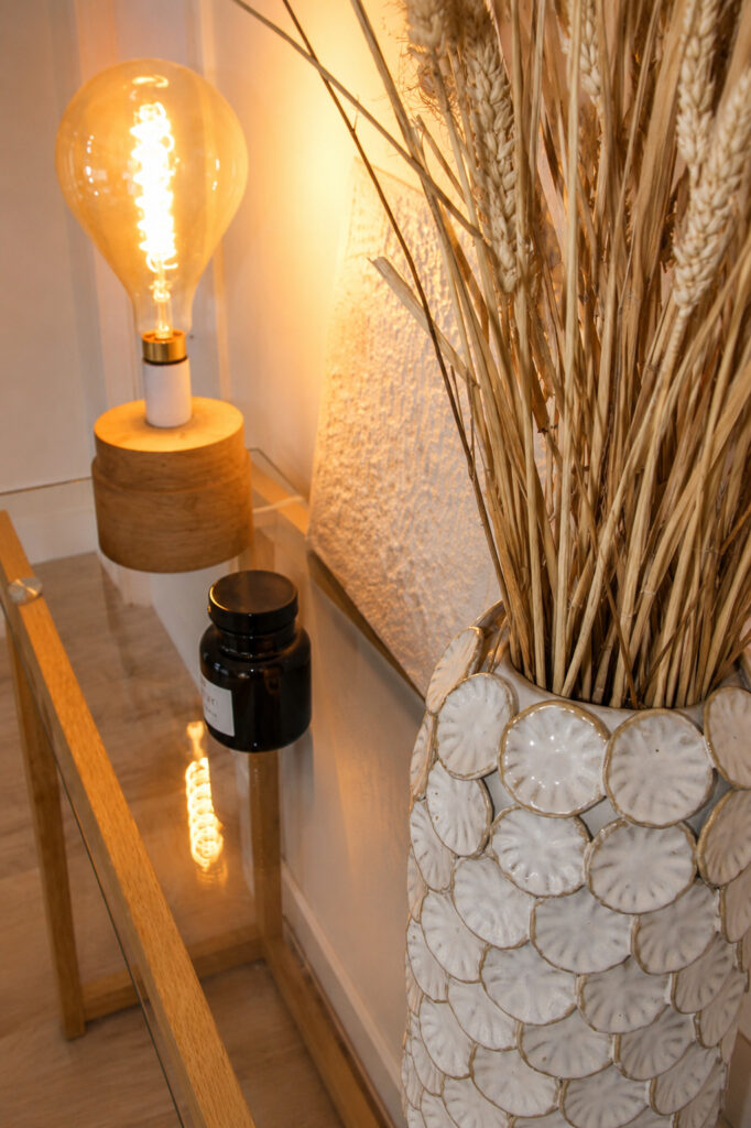 Console décorative avec lampe, vase en céramique et fleurs séchées dans un appartement rénové après sinistre à Nantes.