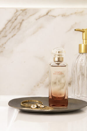 Flacon de parfum et accessoires sur un plan de toilette en céramique dans une rénovation d'appartement ancien à Nantes.