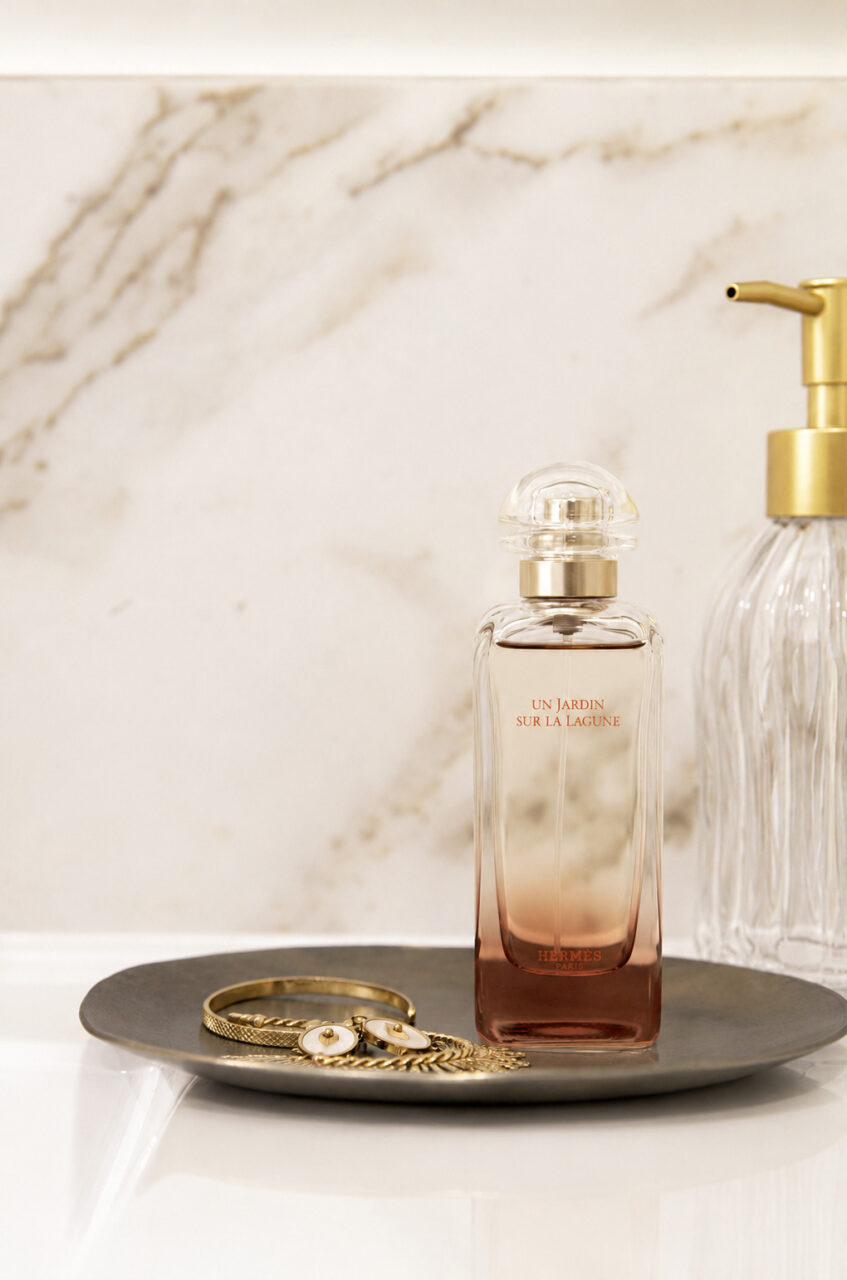 Flacon de parfum et accessoires sur un plan de toilette en céramique dans une rénovation d'appartement ancien à Nantes.