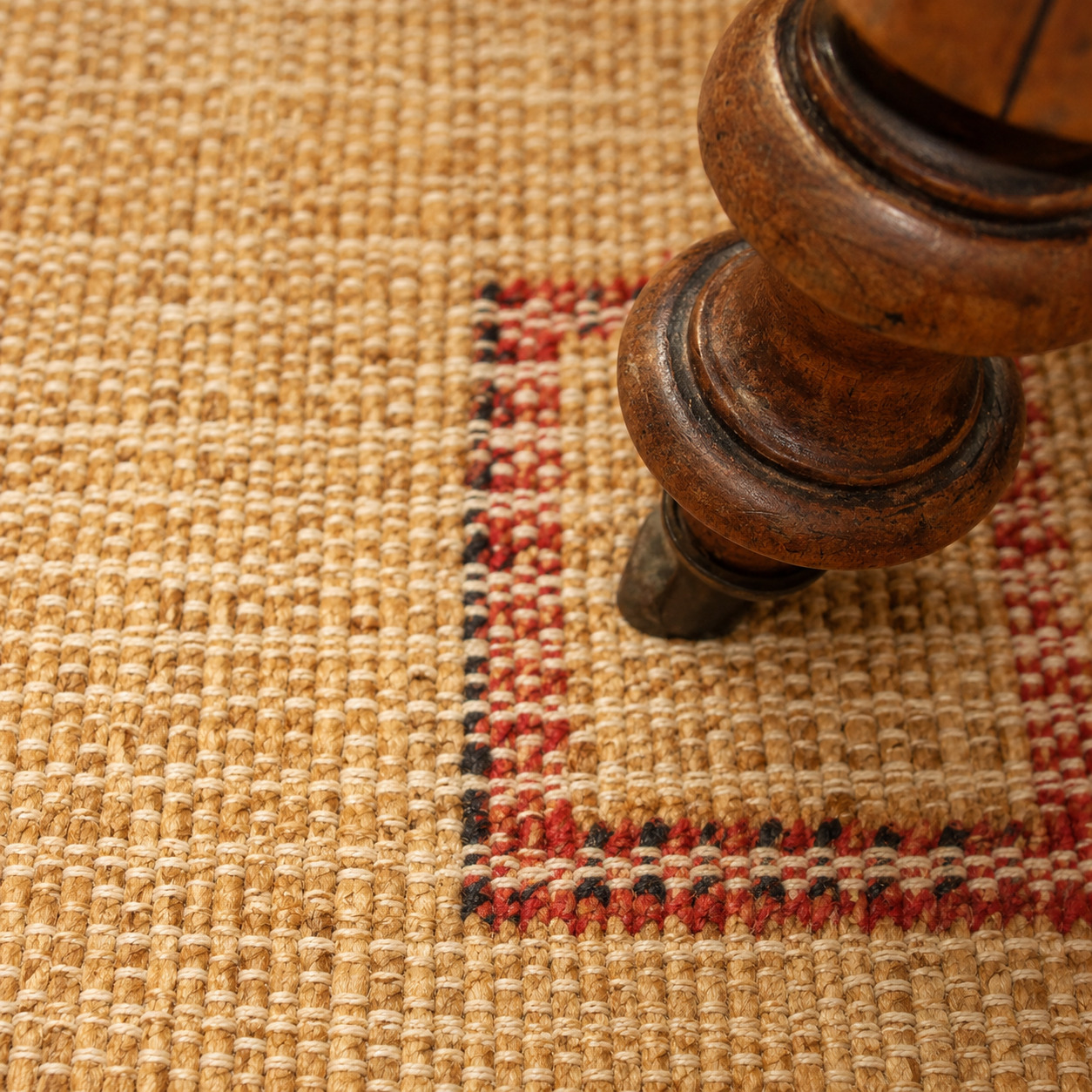 Gros plan sur un tapis en fibres naturelles et un fauteuil ancien dans un appartement rénové après sinistre à Nantes.