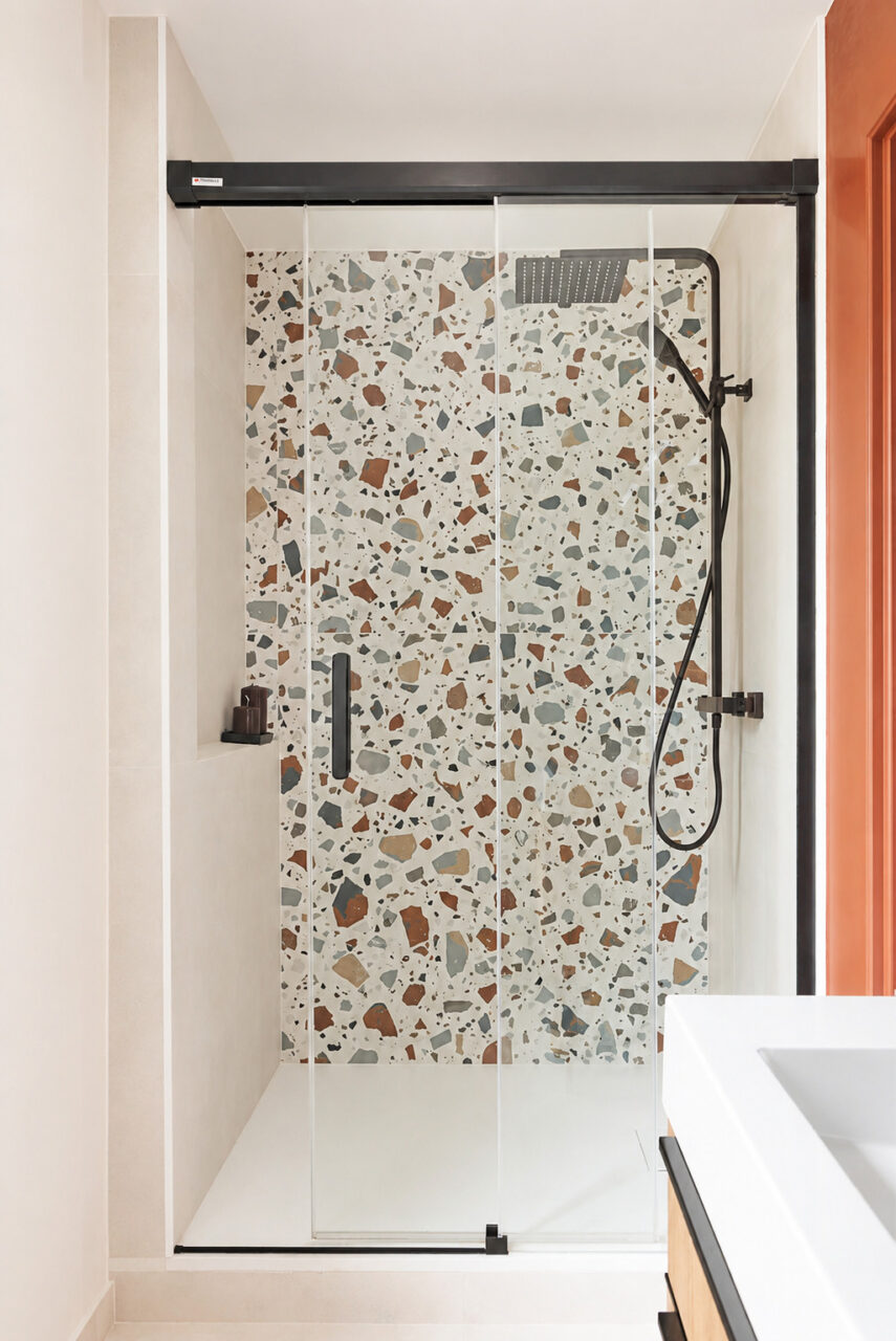 Douche avec receveur extra-plat, paroi vitrée et faïence effet terrazzo dans une salle d'eau optimisée à Vigneux-de-Bretagne.