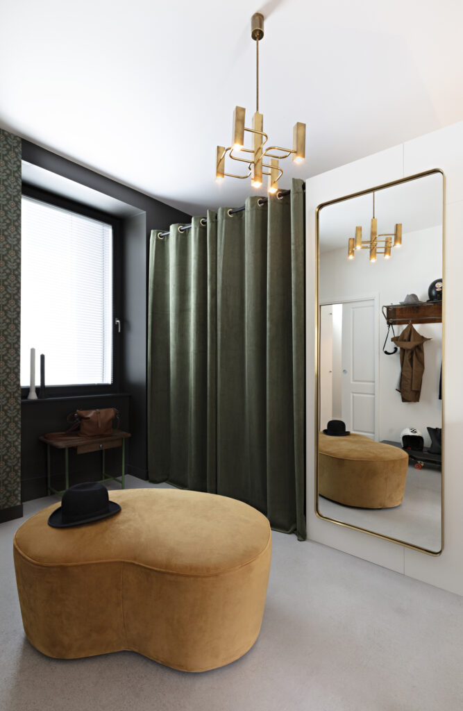 Entrée avec dressing dissimulé derrière un rideau en velours vert, miroir doré et banquette ocre dans une maison décorée à Nantes.