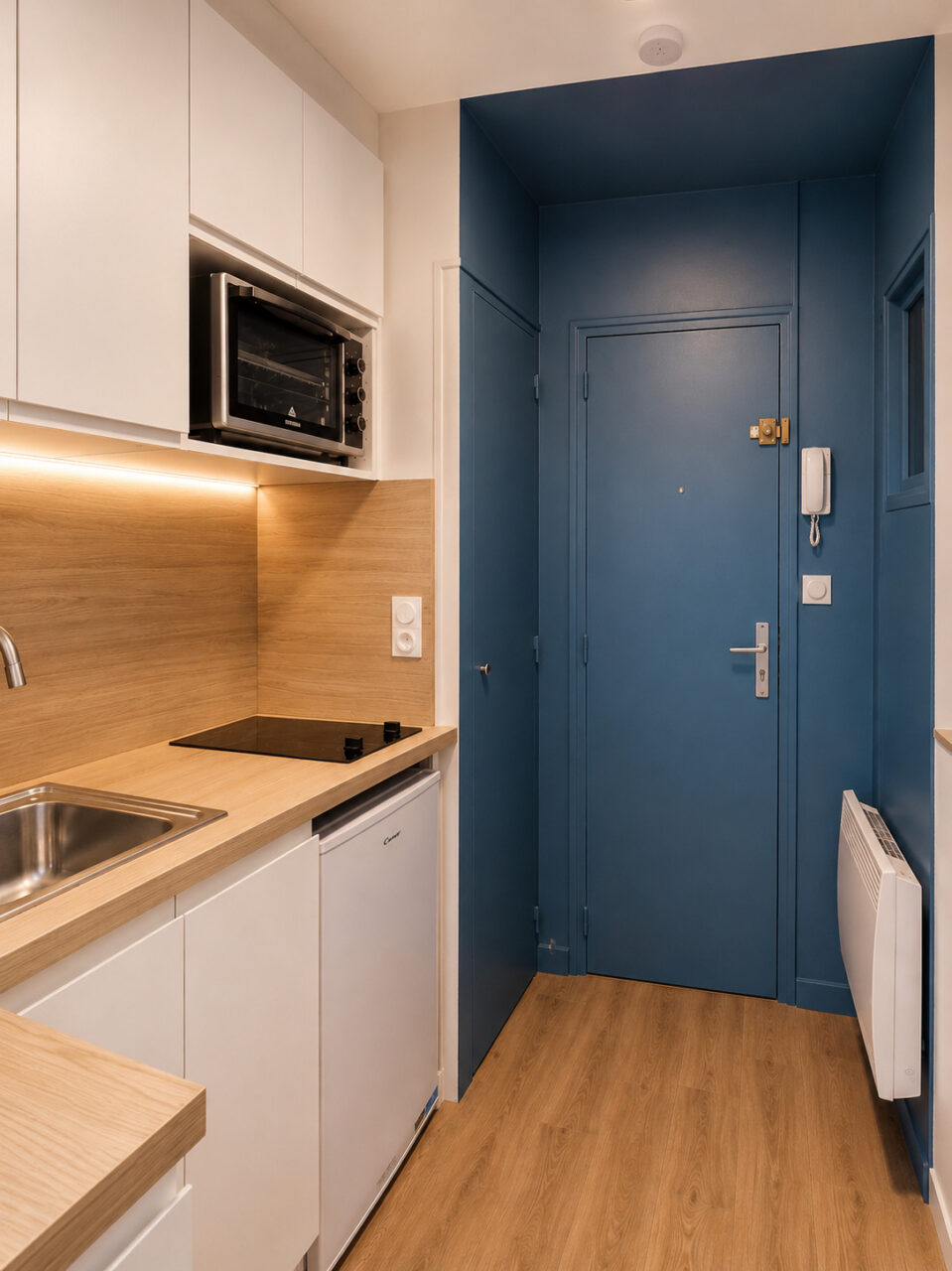 Entrée rénovée avec porte bleu profond dans un studio locatif situé dans un immeuble classé du quartier Graslin à Nantes.