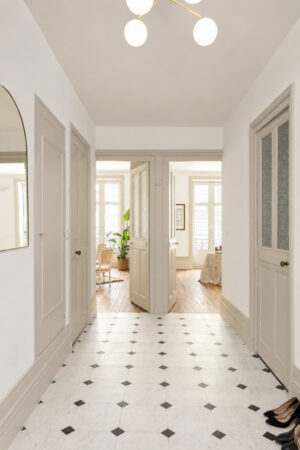 Hall d'entrée avec carreaux à cabochons, portes anciennes restaurées et circulation traversante à Nantes.