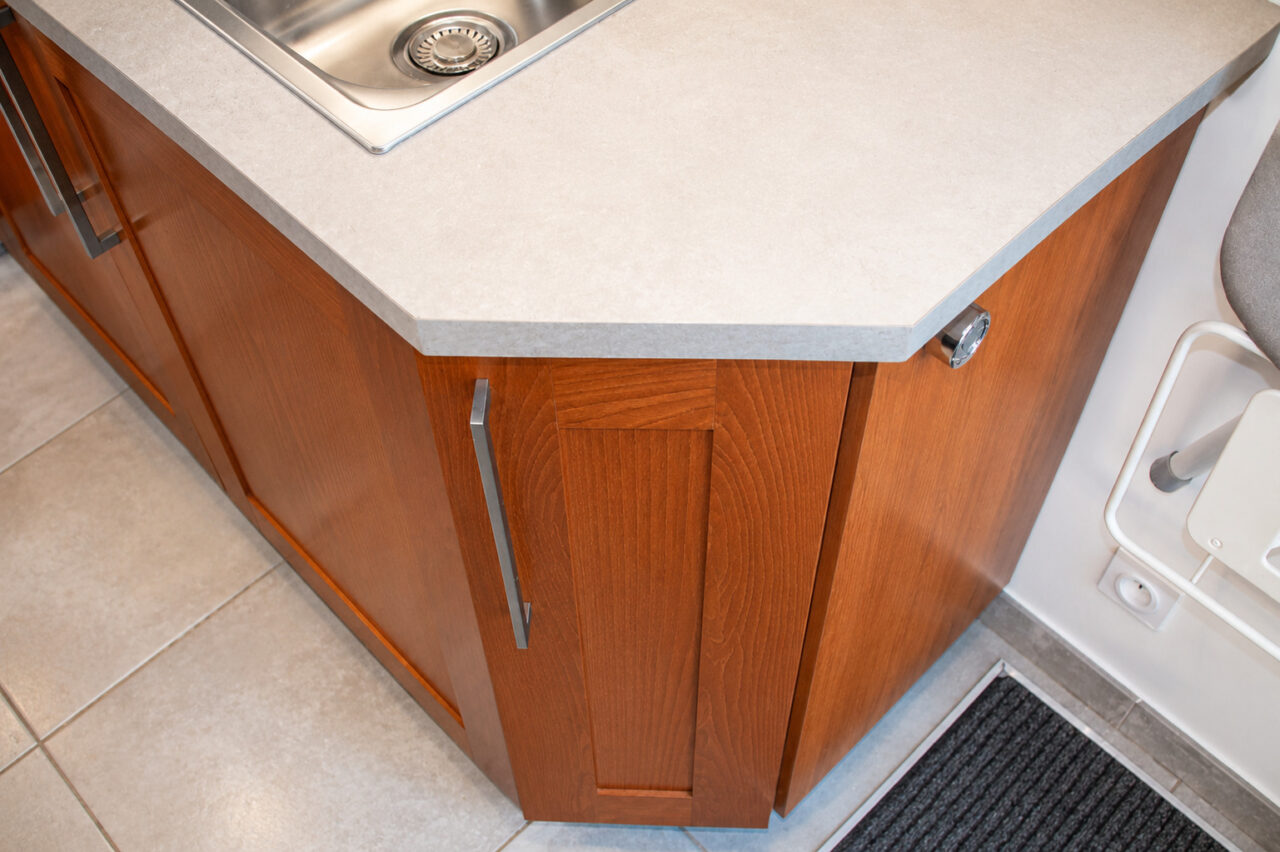 Détail du meuble d'angle en bois et du plan de travail dans une arrière-cuisine buanderie multifonction à Damgan