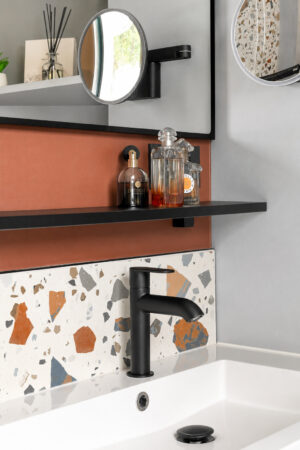 Détail du meuble vasque suspendu avec robinetterie noire, crédence effet terrazzo et miroir dans une salle d'eau optimisée à Vigneux-de-Bretagne.