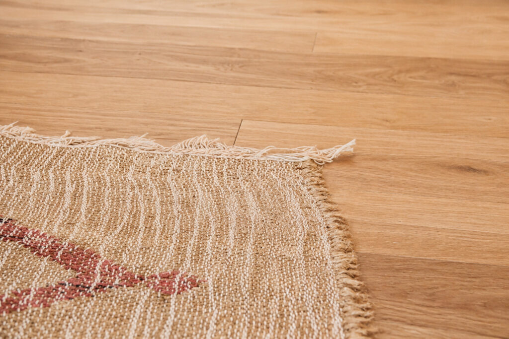 Gros plan sur un parquet en bois clair et un tapis dans un appartement rénové après sinistre à Nantes.
