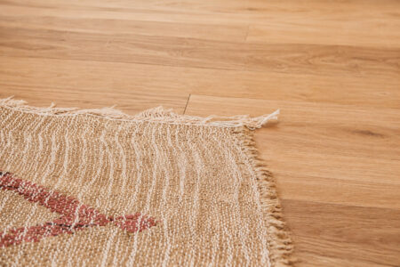 Gros plan sur un parquet en bois clair et un tapis dans un appartement rénové après sinistre à Nantes.