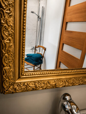Reflet de la baignoire et d'une chaise ancienne dans le miroir d'une salle de bain sous combles à Sautron