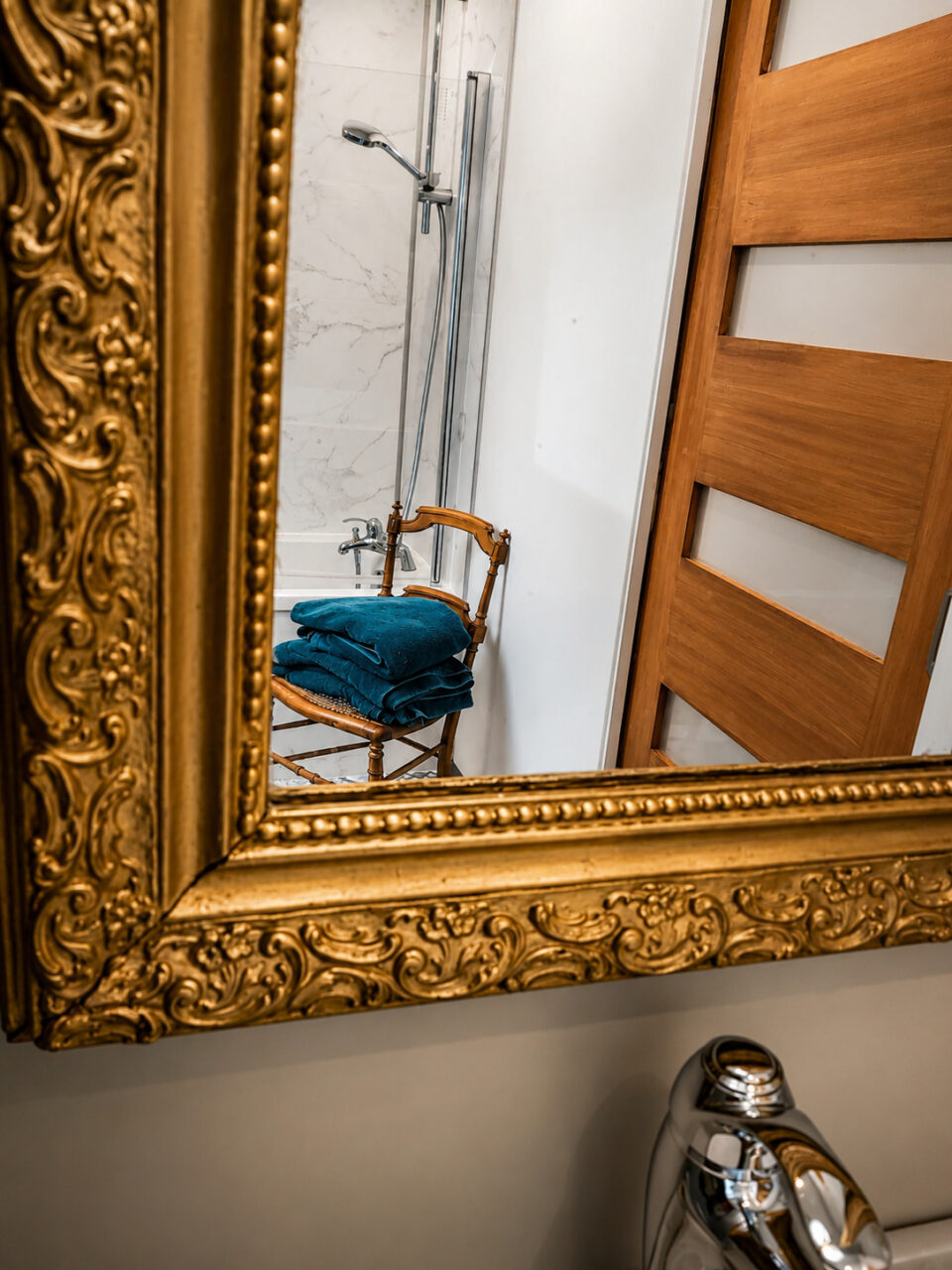 Reflet de la baignoire et d'une chaise ancienne dans le miroir d'une salle de bain sous combles à Sautron