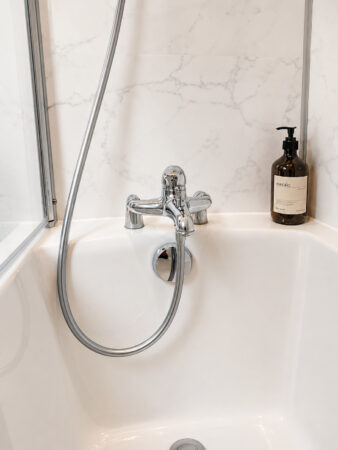 Détail de la robinetterie chromée de la baignoire dans une salle de bain rétro sous combles à Sautron