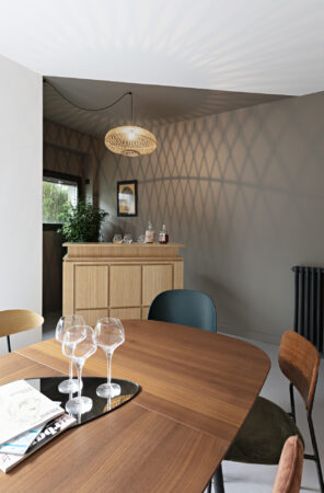 Salle à manger contemporaine avec table en noyer, suspension en fibres naturelles et ambiance chaleureuse dans une maison décorée à Nantes.