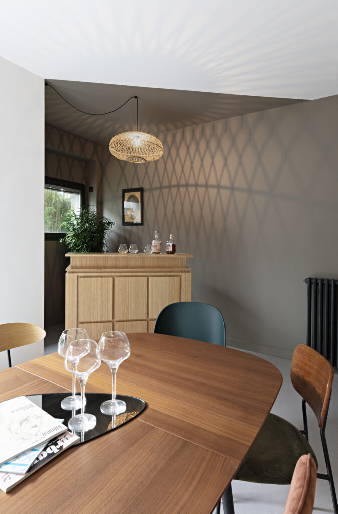 Salle à manger contemporaine avec table en noyer, suspension en fibres naturelles et ambiance chaleureuse dans une maison décorée à Nantes.