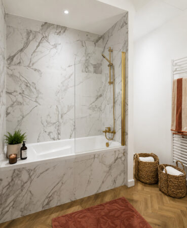 Salle de bain avec baignoire habillée d'un grand carrelage effet marbre et robinetterie laiton dans une rénovation d'appartement ancien à Nantes.