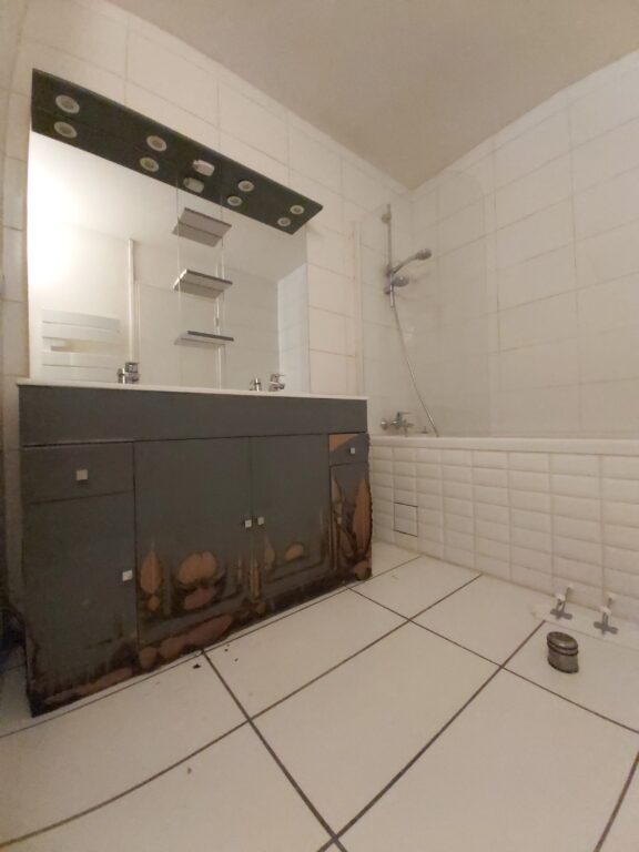 Salle de bains rénovée avec baignoire, meuble double vasque et faïence effet marbre lors d'une rénovation d'appartement après sinistre à Nantes.
