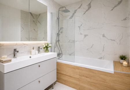 Salle de bains rénovée avec baignoire, meuble double vasque et faïence effet marbre lors d'une rénovation d'appartement après sinistre à Nantes.
