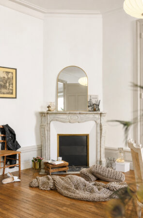 Salon lumineux avec cheminée en marbre restaurée et parquet ancien dans une rénovation d'appartement ancien à Nantes.