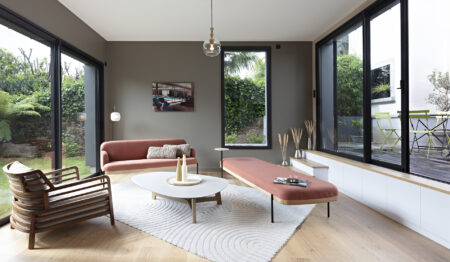 Salon contemporain baigné de lumière avec mobilier aux teintes terracotta et grandes baies vitrées dans une décoration complète de maison à Nantes.