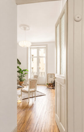 Salon avec parquet ancien restauré, mobilier contemporain et lumière naturelle après rénovation d'un appartement ancien à Nantes.