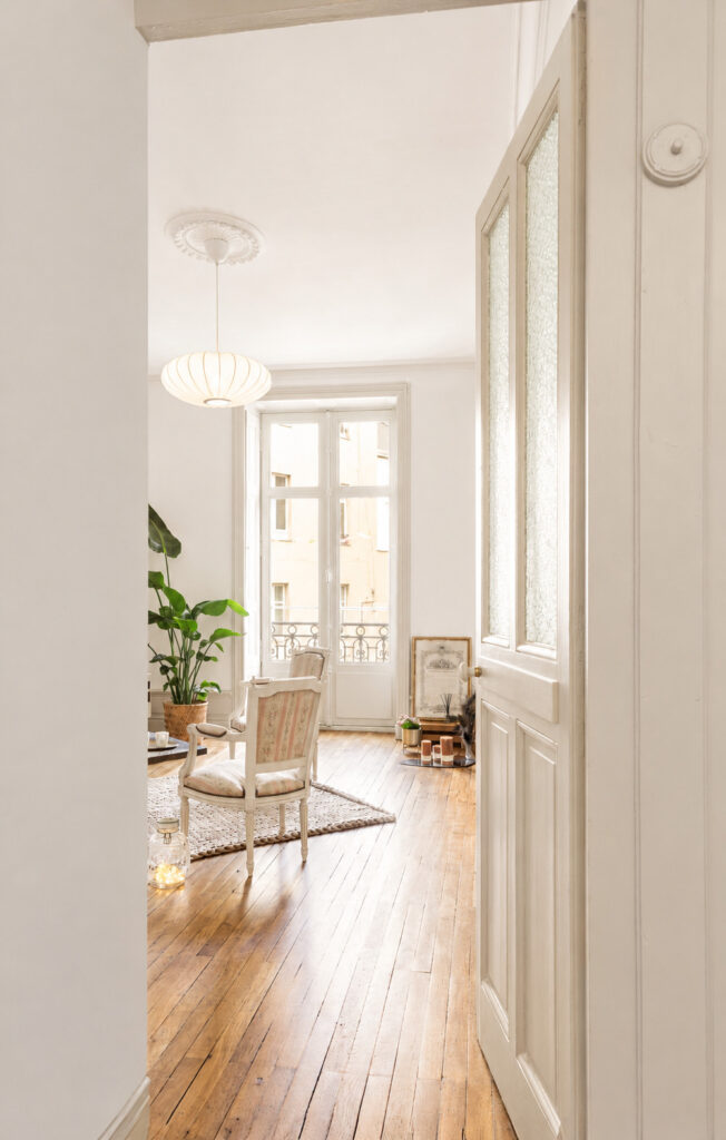 Salon avec parquet ancien restauré, mobilier contemporain et lumière naturelle après rénovation d'un appartement ancien à Nantes.