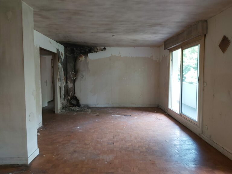 Séjour avant travaux avec mur endommagé par un incendie lors de la rénovation après sinistre à Nantes