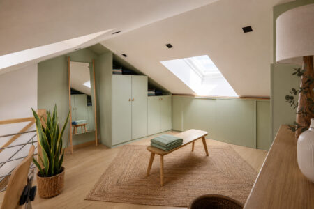 Vue d'ensemble du dressing sous pente aménagé dans une suite parentale mezzanine Orvault avec mobilier sur mesure