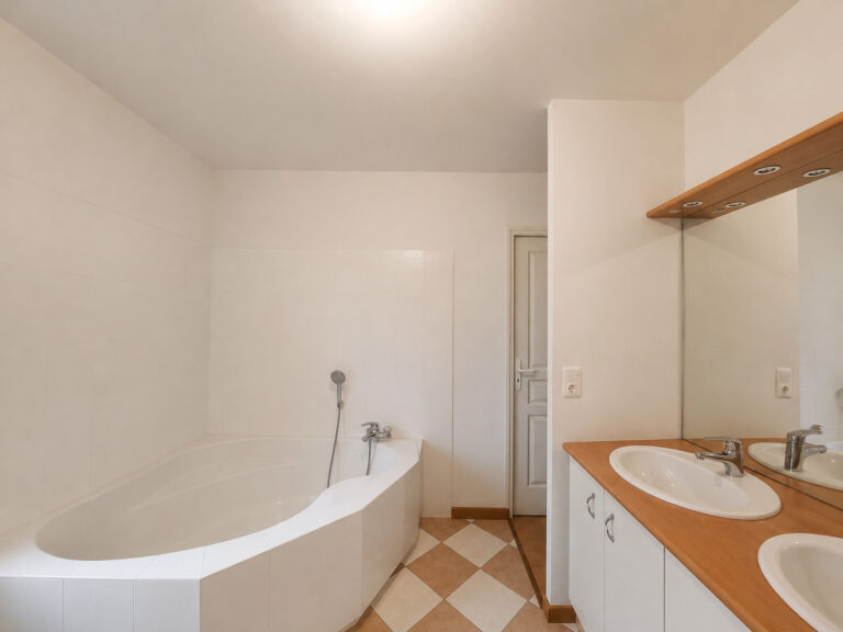 Vue d'ensemble d'une salle de bain avec baignoire et double vasque avant travaux à Vigneux-de-Bretagne